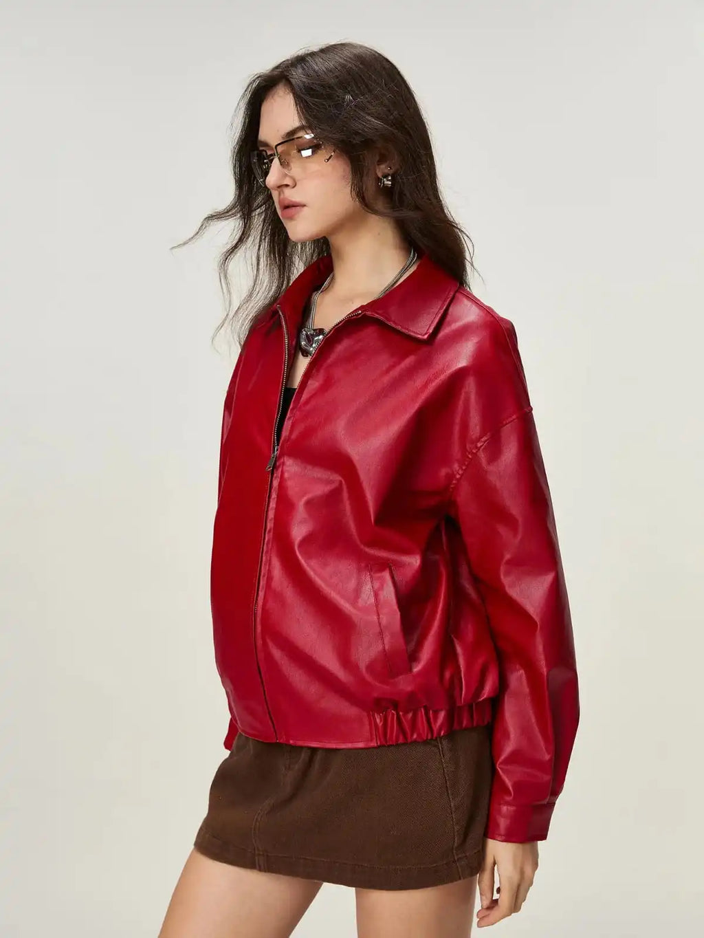 Woman wearing a red leather jacket on a plain background